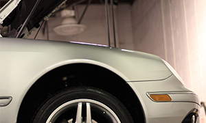 The image shows a silver car parked indoors with its hood open, revealing the engine compartment.